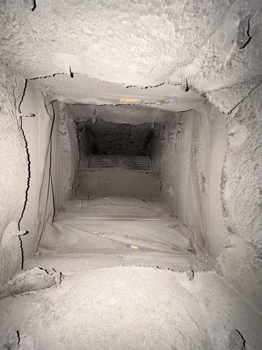 Looking down a rectangular duct trunk line coated in dust